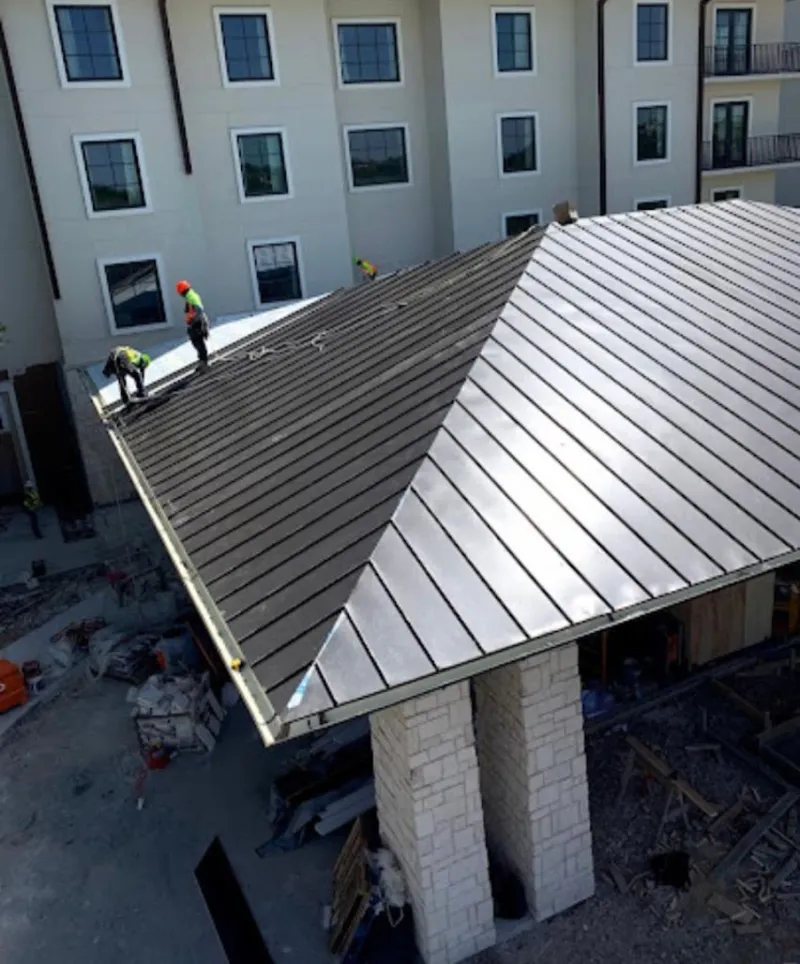 Crew installing standing seam metal roof panels on a commercial project in Bargersville